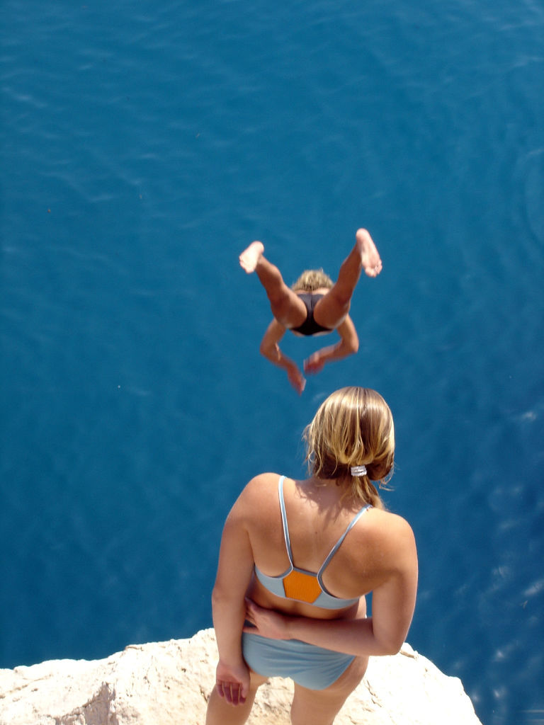 Two girls diving in a clear blue sea in Croatia.