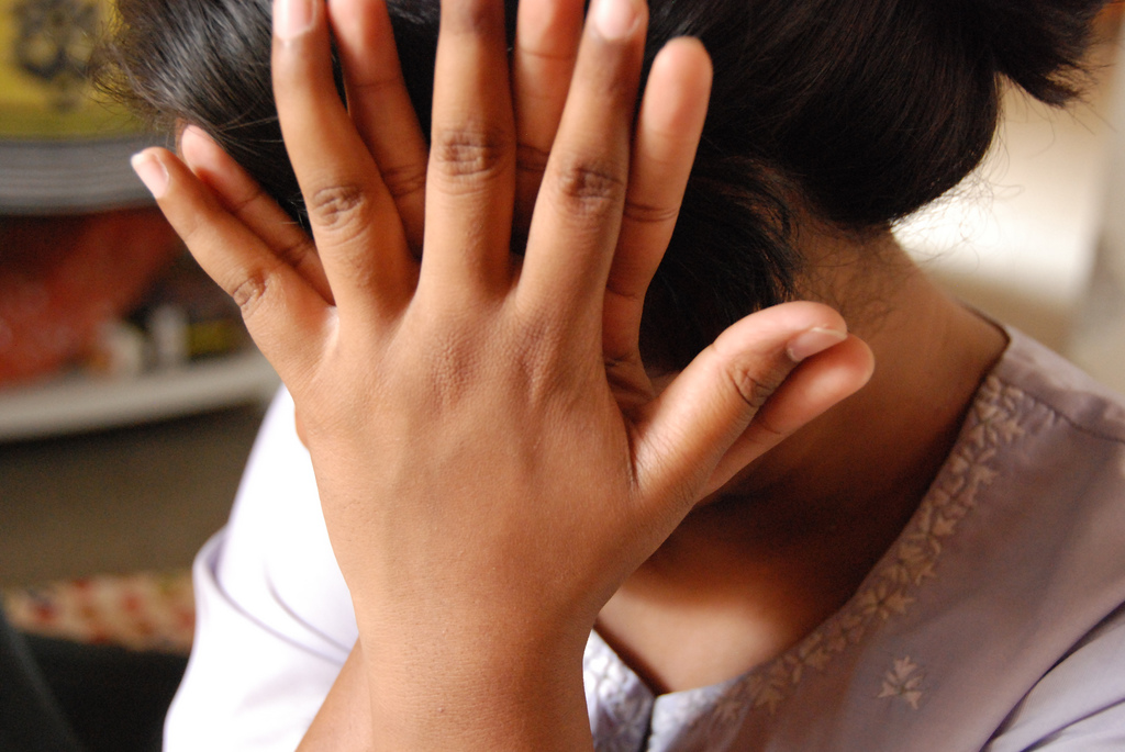 A shy girl covering her face with her hands.